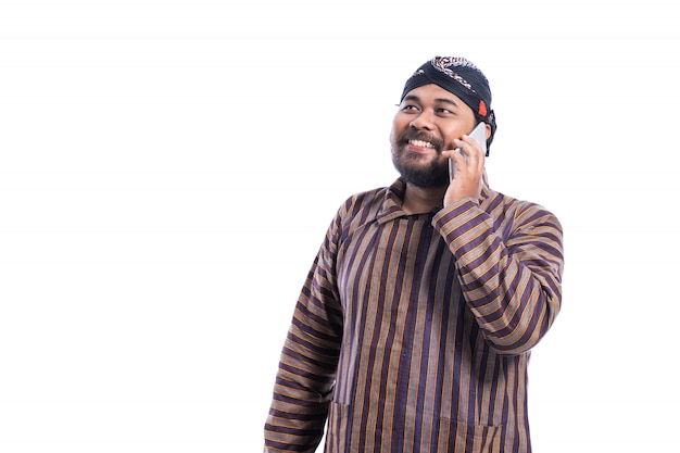 Happy man with Javanese traditional lurik shirt using a phone