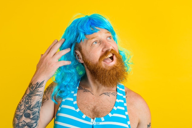 Foto l'uomo felice con salvagente, costume da bagno e parrucca blu si comporta come una donna felice