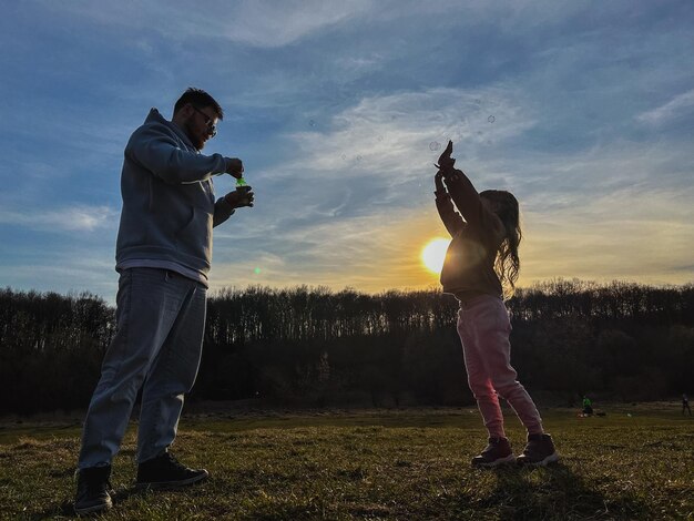 Foto uomo felice con la bambina che gioca con le bolle di sapone