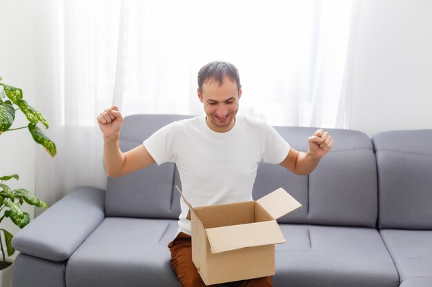 Photo happy man with an open box in an apartment