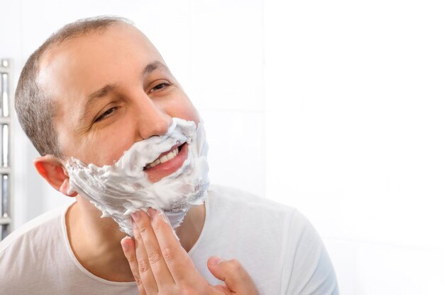 Happy man with shaving foam for facial hygiene