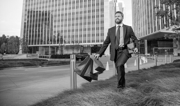 Happy man with shopping bags and present box walk outside the office copy space purchase