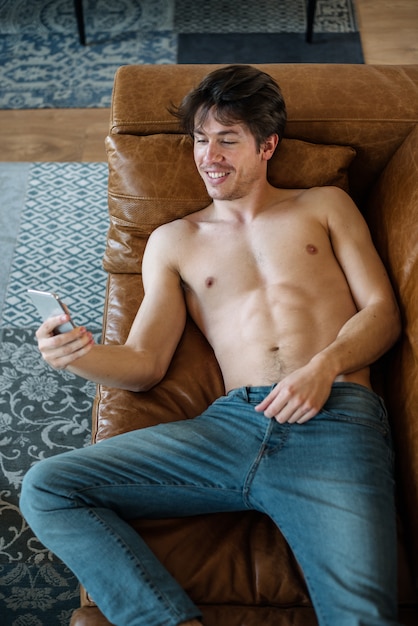 Happy man with smartphone on couch