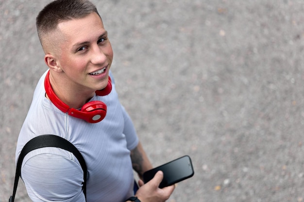 Foto uomo felice con uno smartphone sorride e guarda la telecamera con la testa in alto