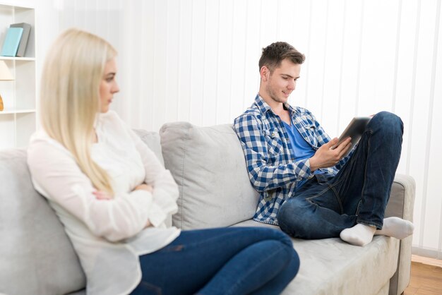 The happy man with a tablet sit near woman on the sofa