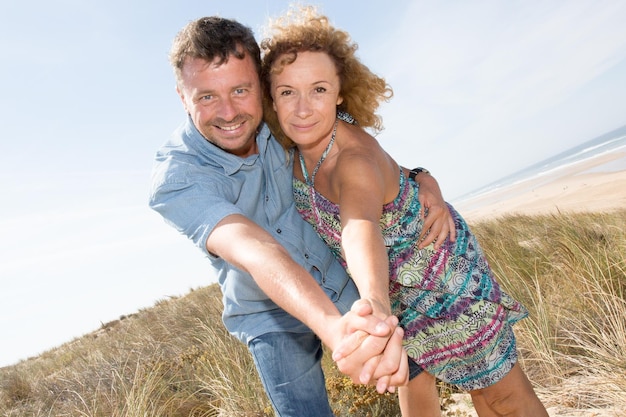 Uomo e donna felici che si tengono per mano su una b tropicale deserta