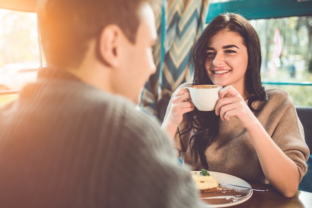 幸せな男と女はカフェでコーヒーを飲みます