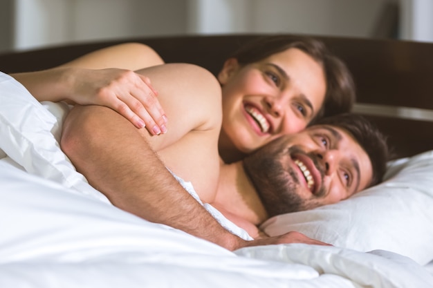 The happy man and woman lay on the bed