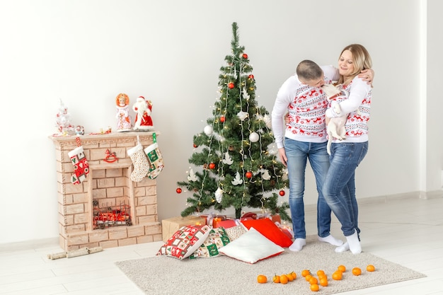 Happy man and woman near Christmas tree at home