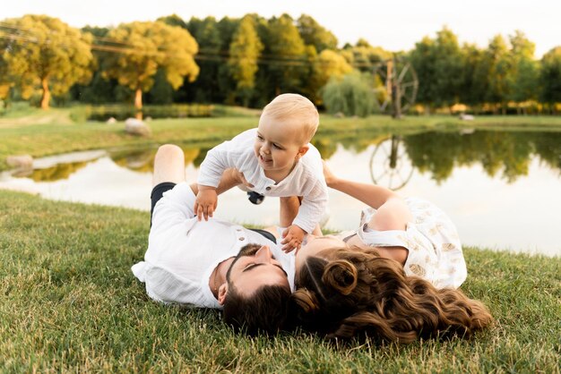 Happy man and woman play with children outside on a sunny day