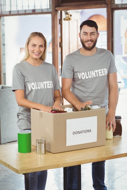 Photo happy man and woman separating donation stuffs in office