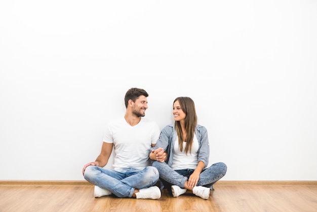 The happy man and woman sit near the empty wall