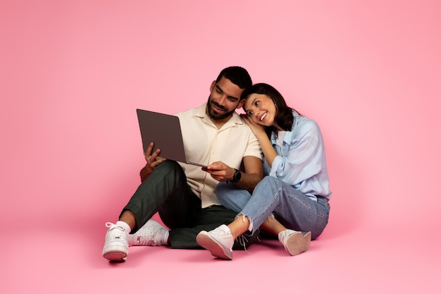 Happy man and woman sitting on floor watching movie online