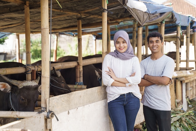 Happy man and woman standing in the farm. eid adha sacrifice concept