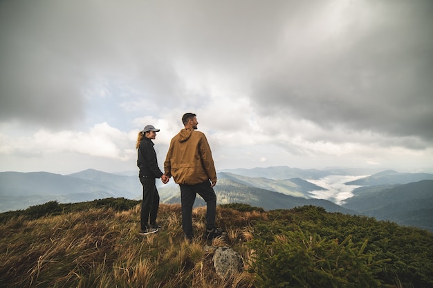 The happy man and a woman standing on a top of a mountain