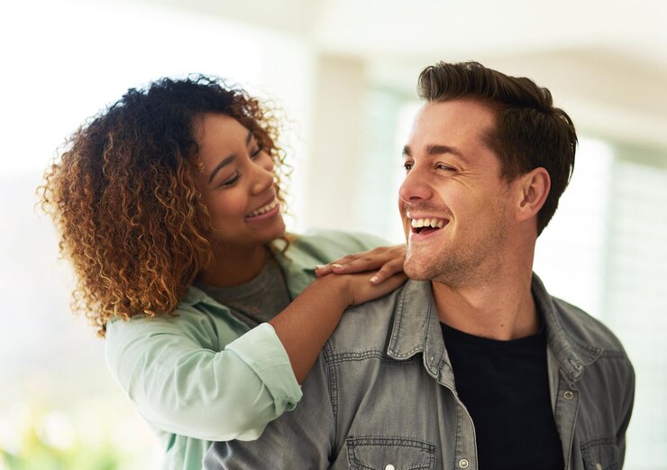 Photo happy man woman and together at home for love romance and affection in living room interracial couple happiness and smile in house for commitment trust or care in relationship and laughter
