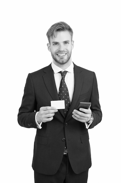 フォーマルなスタイルのスーツを着た幸せなマネージャーは、コピースペース情報のための携帯電話と連絡先カードを保持します