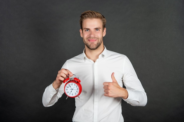 Happy manager give thumbs up holding clock Time management