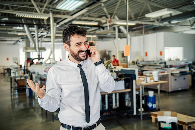 Foto un manager felice che ha una piacevole conversazione con il cliente al telefono in tipografia