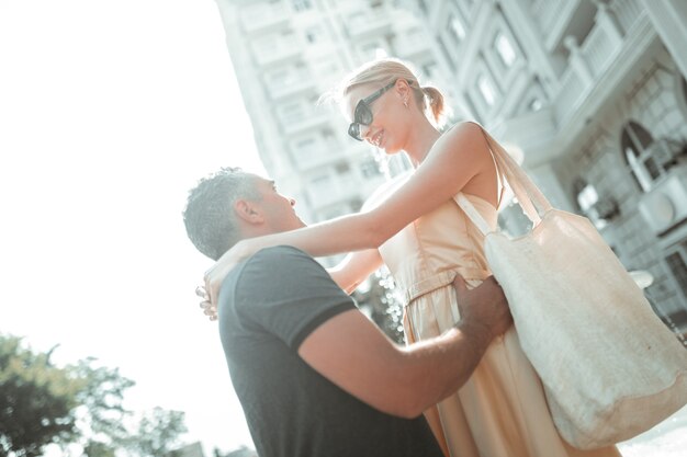 幸せな結婚。陽気な夫婦が目を見て抱き合って外で微笑んでいます。