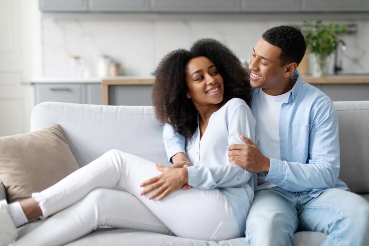 Photo happy married black couple enjoying time on weekend in living room sitting and cuddling on couch