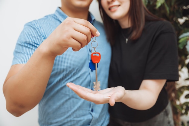 A happy married couple celebrates moving to a new house shows the keys stands in an apartment the concept of a mortgage on real estatekeys closeup