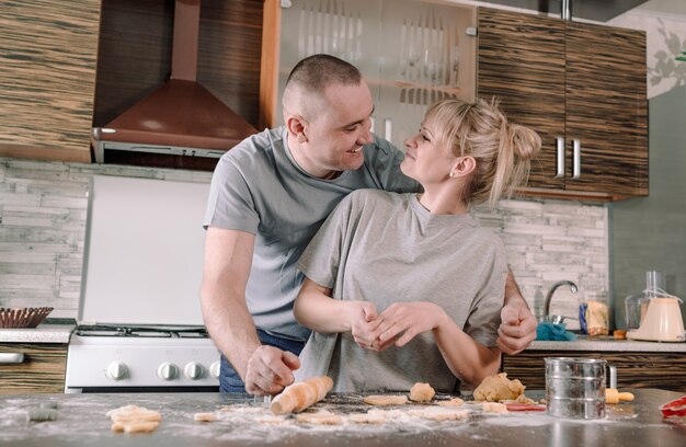 행복한 부부는 서로를 바라보고 부엌에서 쿠키를 만드는 동안 미소를 짓습니다. 가족의 행복 개념