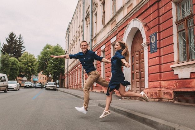 A happy married couple in love runs down the street and rejoice. Beautiful young couple holding hands and smiling while walking along the city street