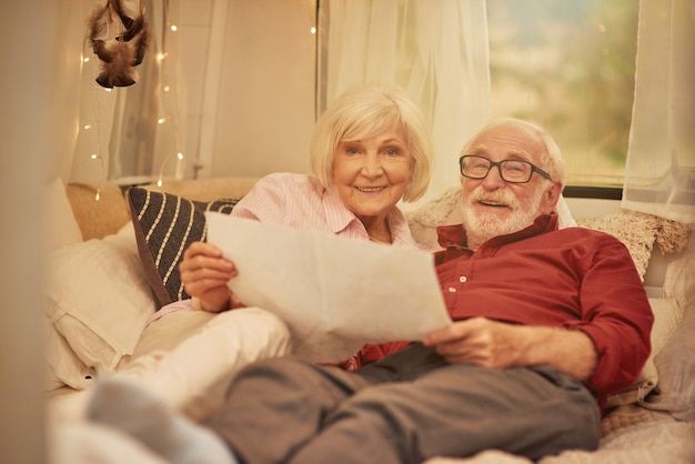 Happy married couple using map while resting in their motorhome