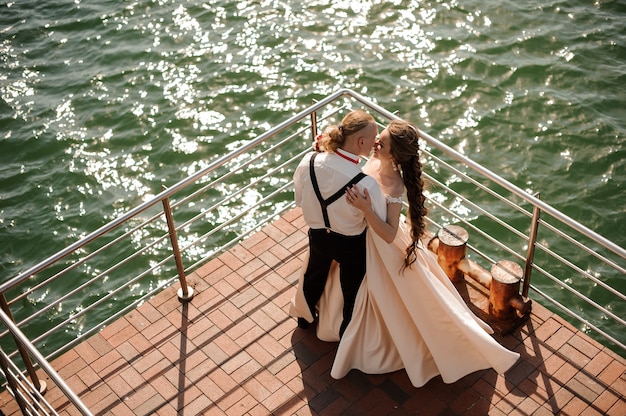 Foto felice uomo sposato e donna in piedi sul molo sul lago. concezione del matrimonio