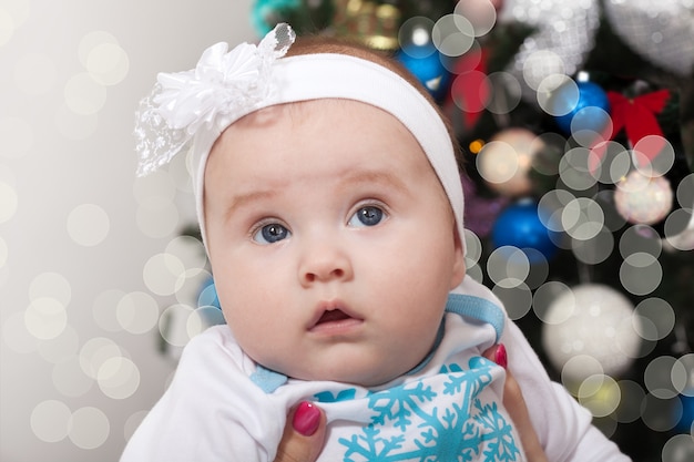 Happy mather with little baby near Christmas tree