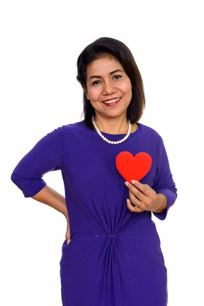  happy mature Asian woman holding red heart isolated against white wall