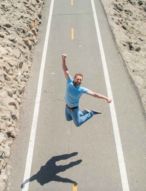 Photo happy mature athletic man jumping on road outdoor motivation