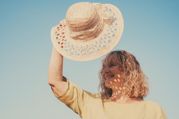 Foto felice donna bionda matura che esamina la distanza sentendosi positiva e sognando ottimista