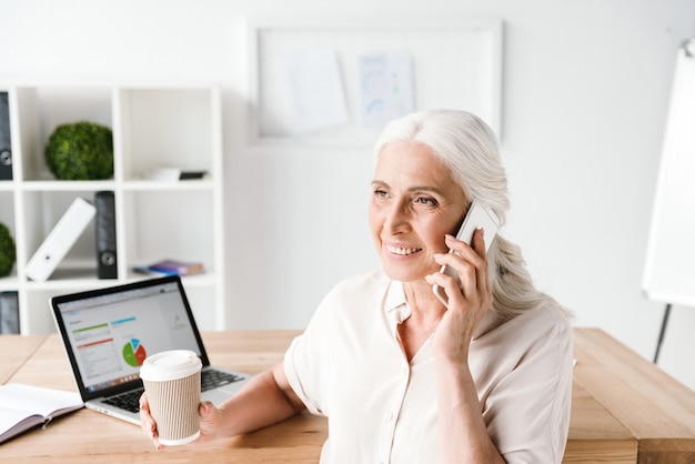 Happy mature business woman talking on mobile