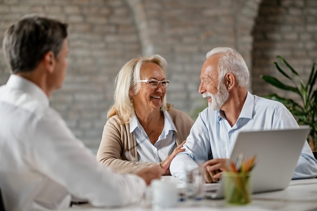 Happy mature couple communicating while having consultations with insurance agent in the office