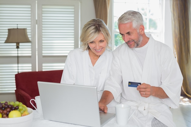 家庭でオンラインショッピングをしている幸せな成熟した夫婦