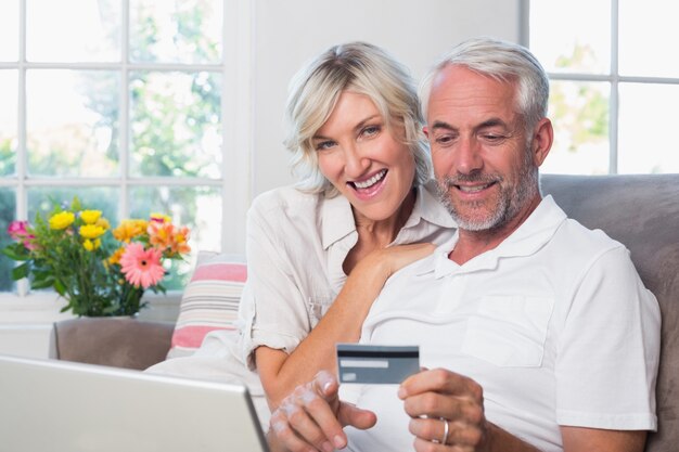 Happy mature couple doing online shopping at home