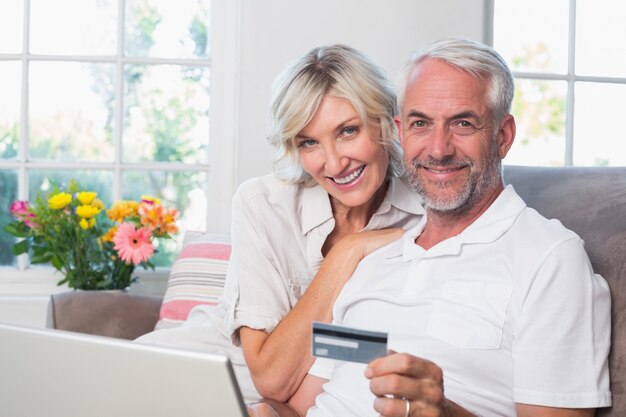 Happy mature couple doing online shopping at home