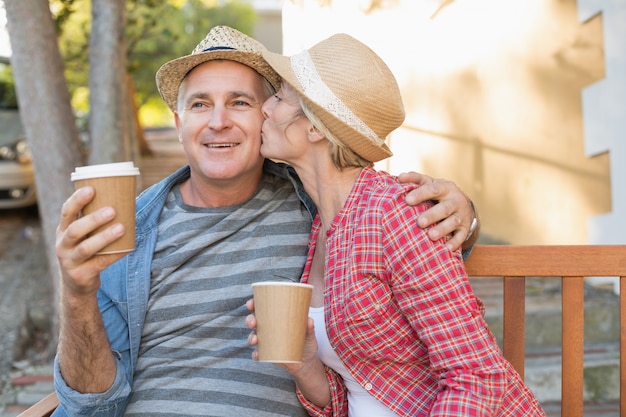 都市のベンチでコーヒーを飲む幸せな成熟したカップル