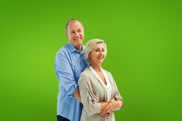 Happy mature couple embracing each other against green vignette