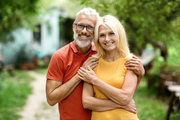 Happy mature couple embracing while standing outdoors in their garden