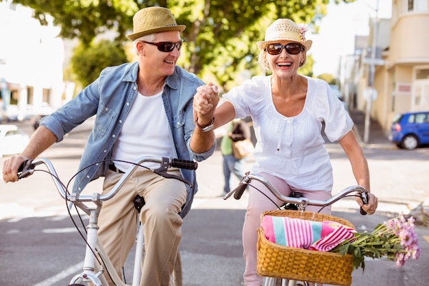 Happy mature couple going for a bike ride in the city