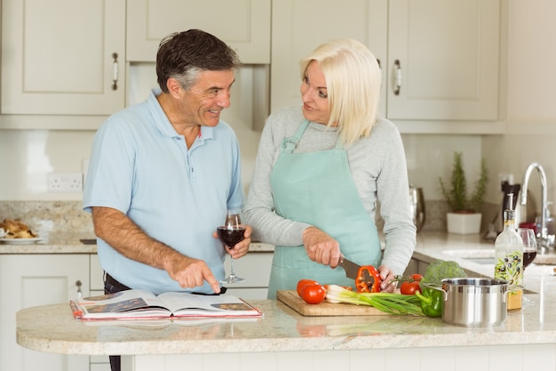 Happy mature couple having red wine while making dinner