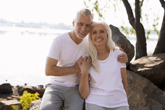 Happy mature couple looking pleased and smiling outdoors on the rocks