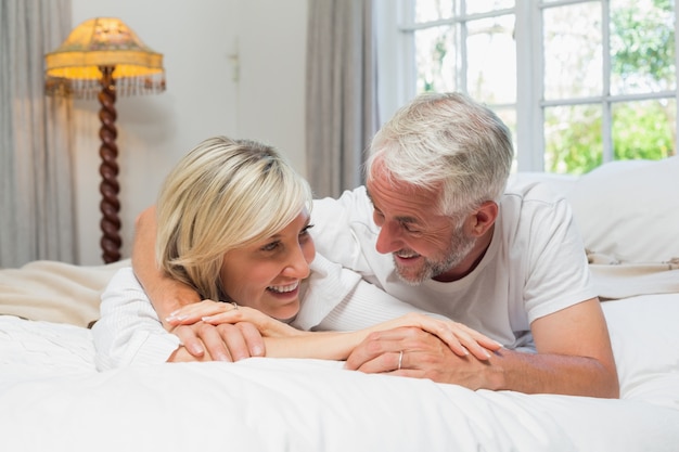 Happy mature couple lying in bed at home