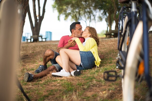 Happy mature couple lying on grass and kissing