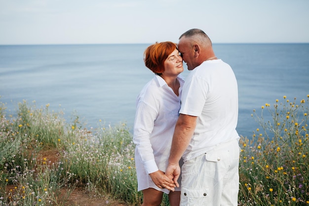 幸せな成熟したカップルは、ビーチで晴れた日にポーズをとる