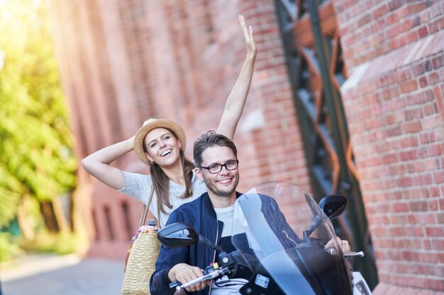 Happy mature couple riding a scooter in the city on a sunny day