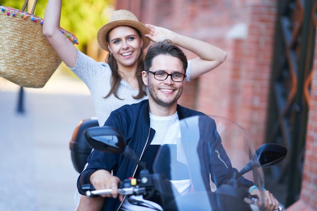 Happy mature couple riding a scooter in the city on a sunny day